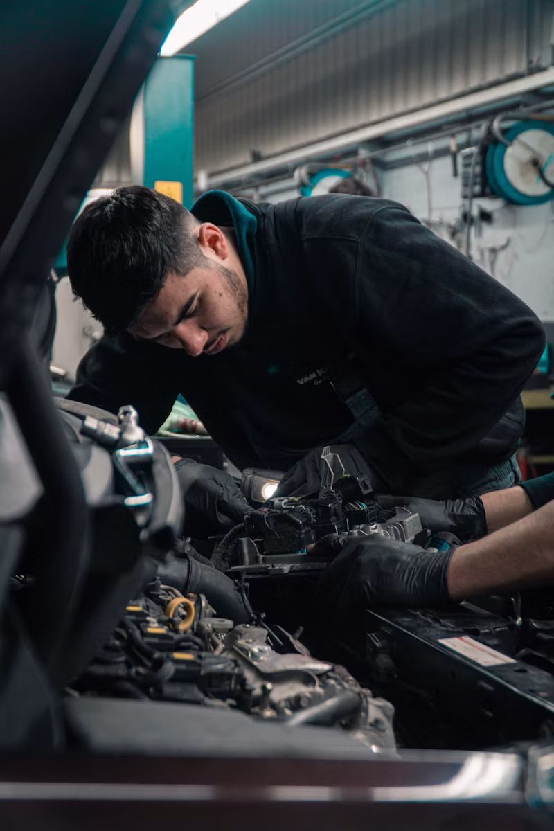 Automotive mechanic working on a car engine in a shop bay